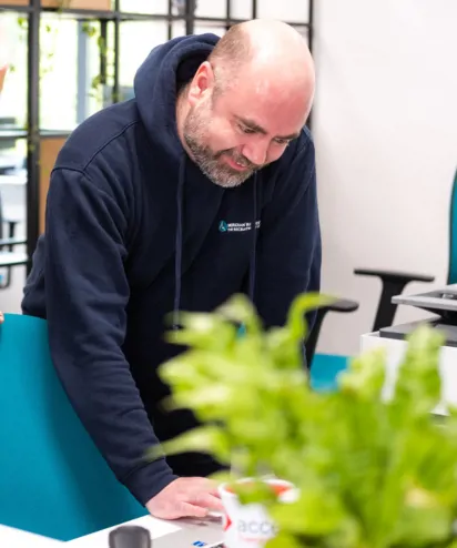 IT systems administrator in navy blue branded hoodie looking at computer screen
