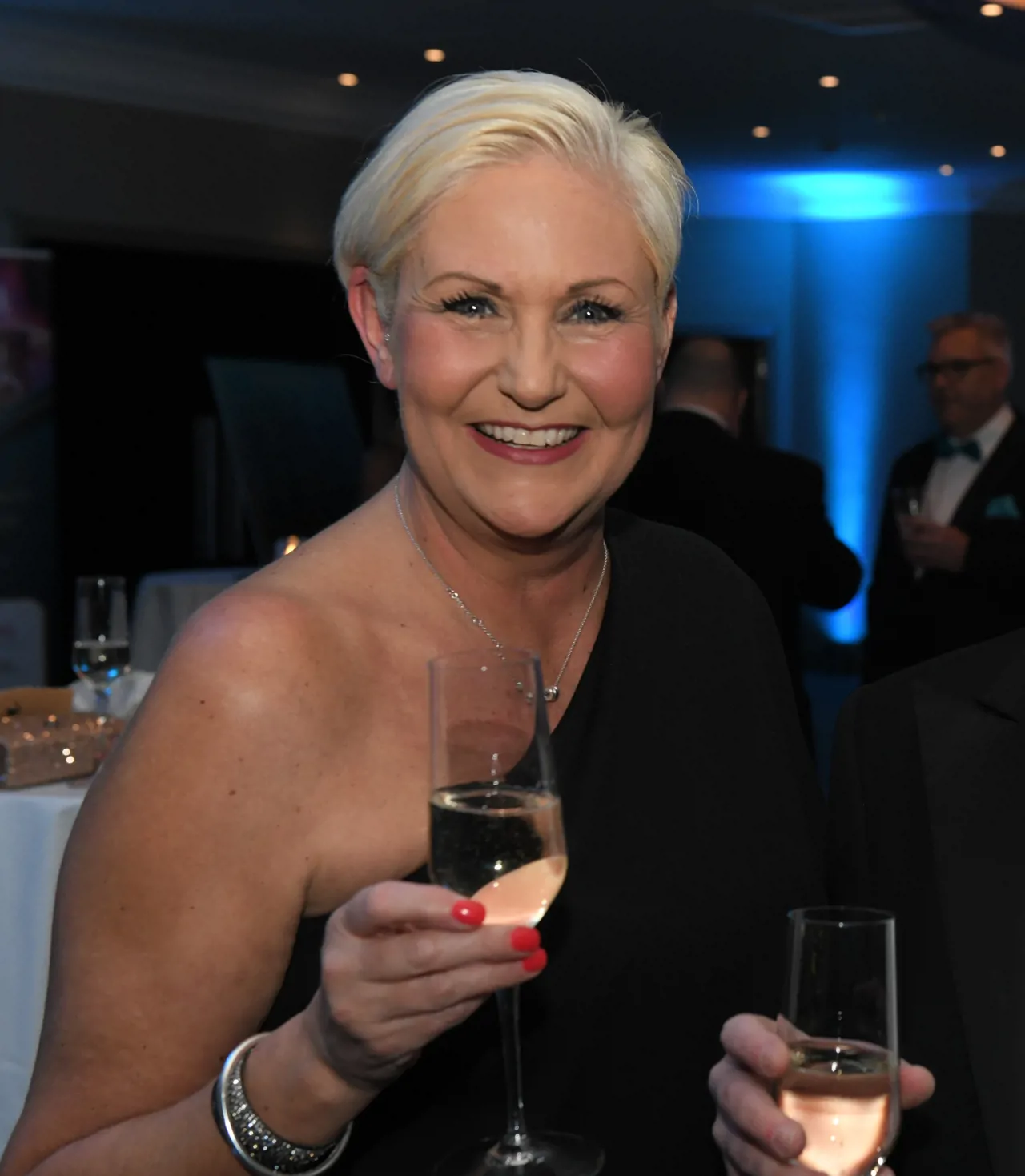 Portrait of Jayne smiling at awards ceremony holding a glass of champagne